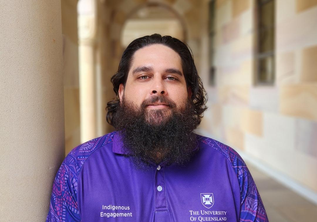 Bearded man standing under sandstone pillars in the UQ Great Court 