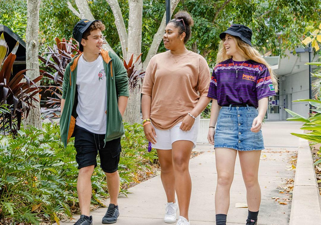 Three students walk in the UQ grounds.