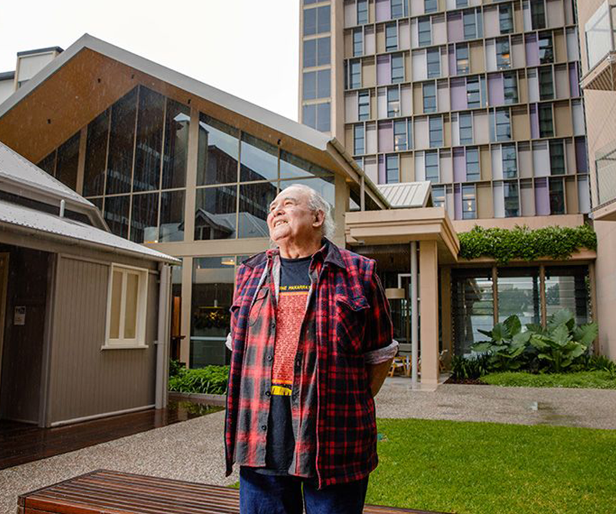 Kev Carmody smiling in front of Kev Carmody House.