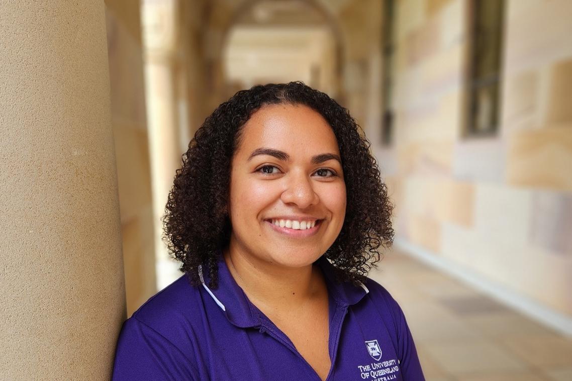 Young woman standing under sandstone pillars in the UQ Great Court.