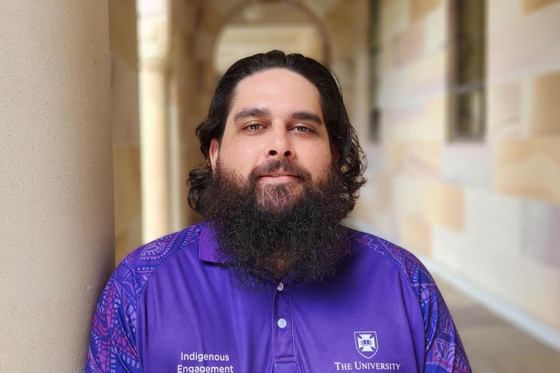 Bearded man standing under sandstone pillars in the UQ Great Court 