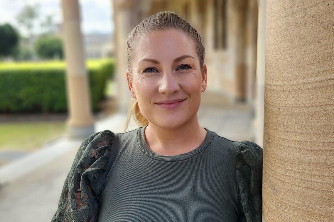 Young woman standing under sandstone pillars in the UQ Great Court