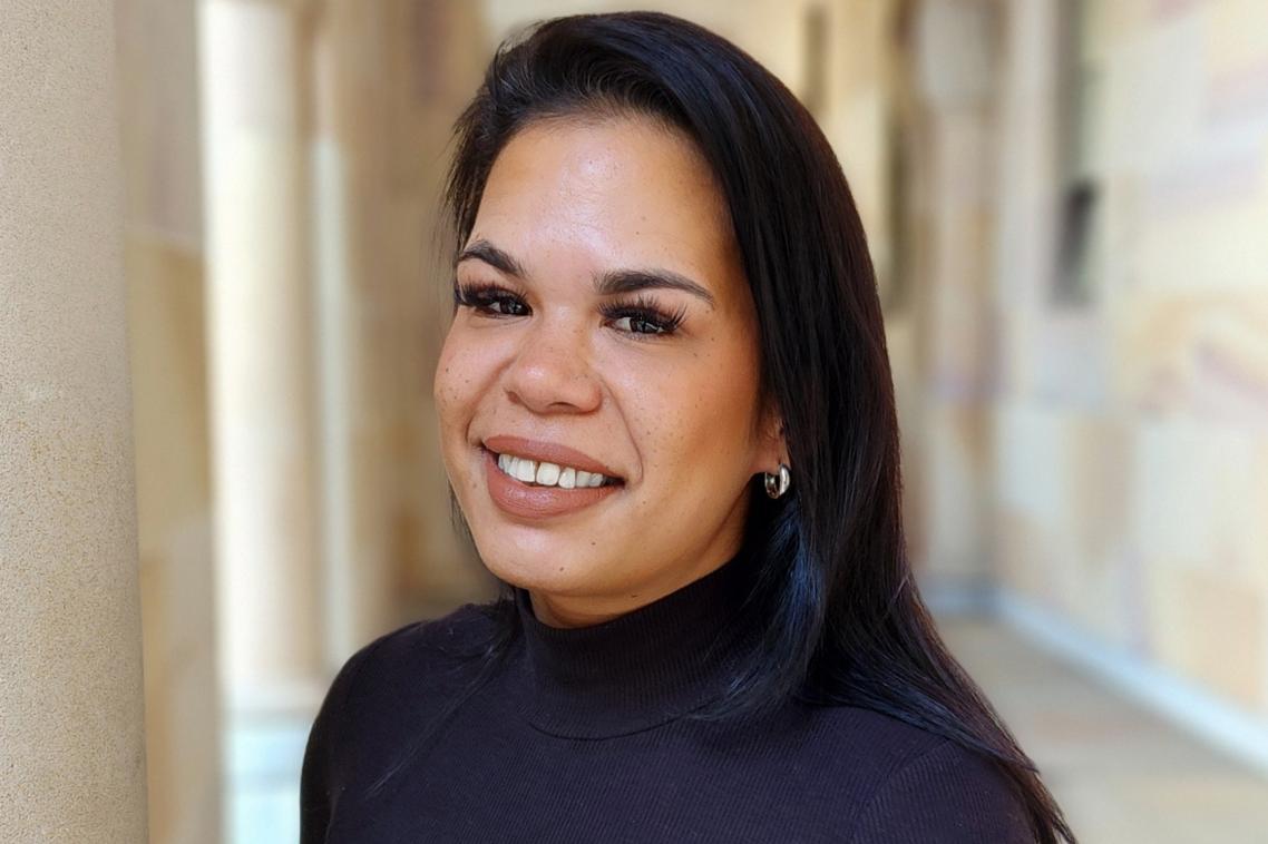 Woman dressed in black standing under sandstone pillars in the UQ Great Court